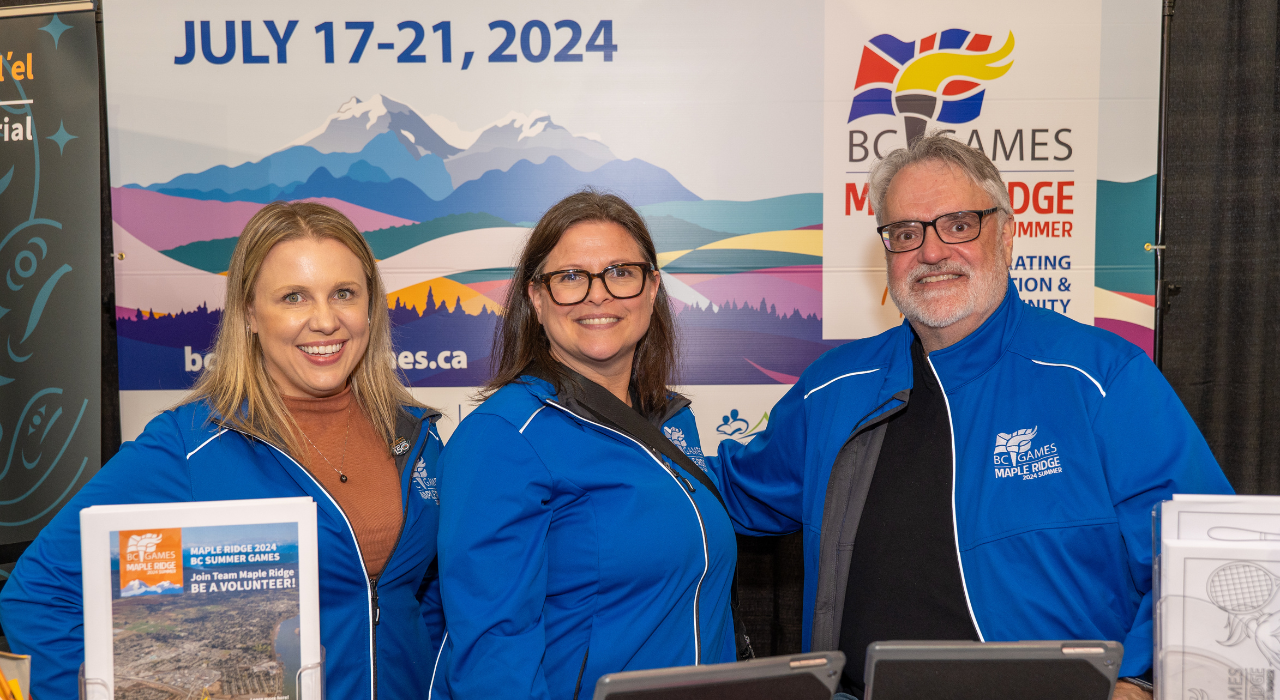 Three Maple Ridge volunteers dressed in Games jackets pose for a photo at a volunteer event.